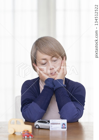 A senior woman thinking about returning her driver's license in the living room 134512522