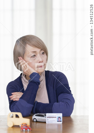 一位老婦人在客廳考慮是否要歸還她的駕照。 一位老婦人在客廳考慮是否要歸還她的駕照。 134512526