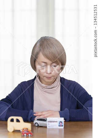 A senior woman thinking about returning her driver's license in the living room A senior woman thinking about returning her driver's license in the living room 134512531