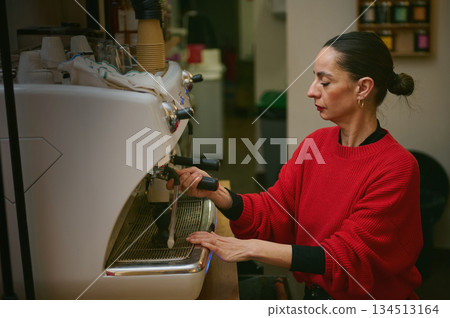 A Hispanic cafe owner brews coffee with an espresso machine, expressing hospitality and small business spirit. A Hispanic cafe owner brews coffee with an espresso machine, expressing hospitality and small business spirit. 134513164