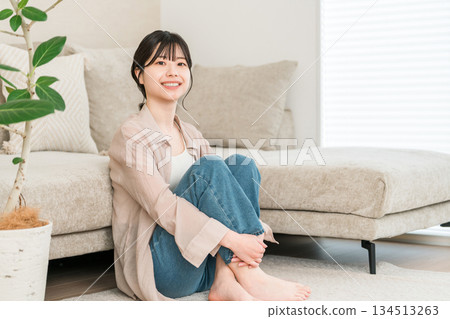 在家的客廳裡微笑的年輕亞洲女性放鬆 在家的客廳裡微笑的年輕亞洲女性放鬆 134513263