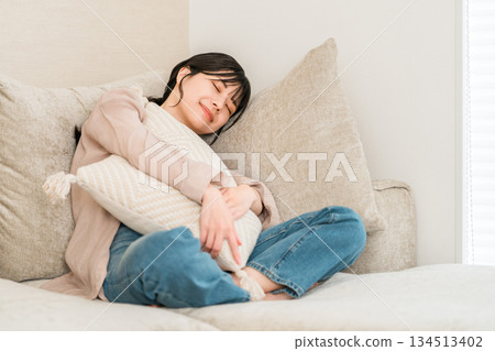 Young Asian woman falling asleep on the sofa in the living room at home Young Asian woman falling asleep on the sofa in the living room at home 134513402