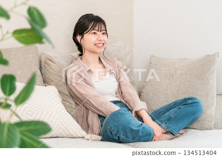 在家客廳的沙發上放鬆的微笑年輕亞洲女性 134513404