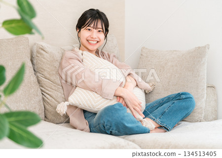 Smiling young Asian woman relaxing on the sofa in the living room at home 134513405