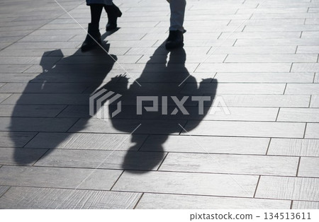 Shadows of people walking on the cobblestone sidewalk in the setting sun Shadows of people walking on the cobblestone sidewalk in the setting sun 134513611