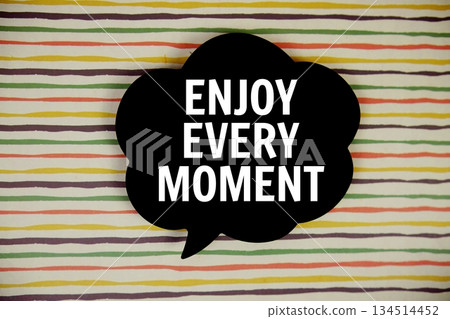 Enjoy Every Moment text with speech bubble top view on colorful stripes background Enjoy Every Moment text with speech bubble top view on colorful stripes background 134514452