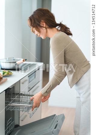 A young Asian woman using a dishwasher in a system kitchen 134514712