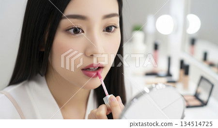 Woman applying pink lip gloss 134514725