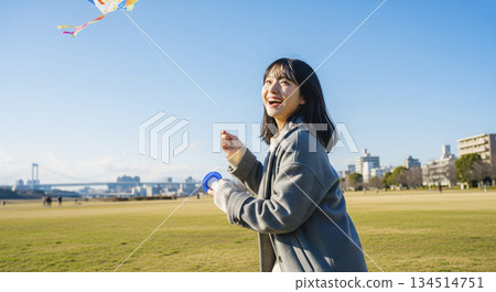 A woman flying a kite on the riverbank 134514751