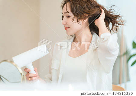 女人用吹風機吹乾頭髮（護髮） 134515350