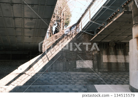 The sharp winter light and shadows illuminating the inorganic wall beneath the elevated railway 134515579