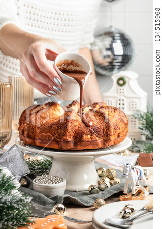 Chocolate marble bundt cake or zebra cake on festive christmas table, woman is pouring chocolate glaze on a cake 134515968