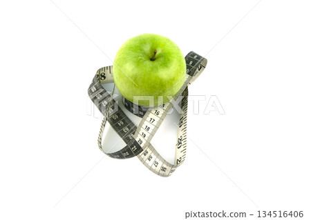 A green apple and a black and white measuring tape. A green apple and a black and white measuring tape. 134516406