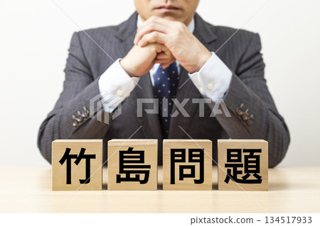 一塊寫著「竹島問題」字樣的磚塊和一個商人 一塊寫著「竹島問題」字樣的磚塊和一個商人 134517933