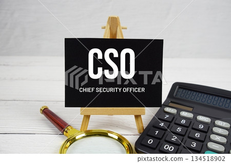 CSO Chief Security Officer text with magnifying glass and calculator on wooden background 134518902