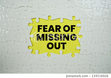Jigsaw puzzle with a missing piece with "Fear of missing out" on yellow background Jigsaw puzzle with a missing piece with "Fear of missing out" on yellow background 134518926