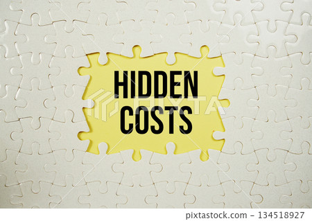 Jigsaw puzzle with a missing piece with "Hidden Costs" on yellow background Jigsaw puzzle with a missing piece with "Hidden Costs" on yellow background 134518927