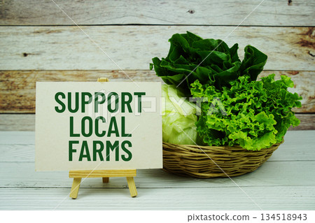 "Support Local Farms" message on a small easel next to a basket of fresh green leafy vegetables "Support Local Farms" message on a small easel next to a basket of fresh green leafy vegetables 134518943