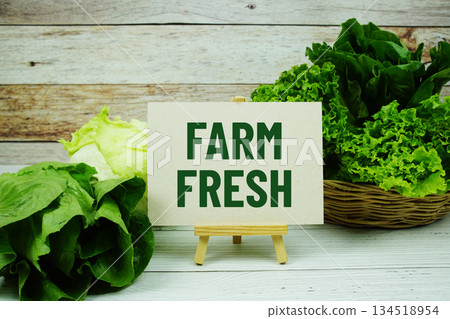 "Farm Fresh" message on a small easel next to a basket of fresh green leafy vegetables "Farm Fresh" message on a small easel next to a basket of fresh green leafy vegetables 134518954