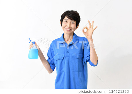 一位身穿工作服的中年亞裔女性,手持清潔噴霧,並比劃著「OK」手勢。 一位身穿工作服的中年亞裔女性,手持清潔噴霧,並比劃著「OK」手勢。 134521233