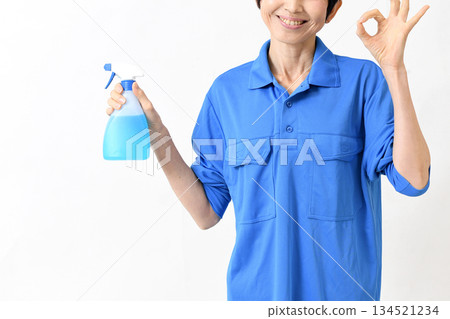 一位身穿工作服的中年亞裔女性,手持清潔噴霧,並比劃著「OK」手勢。 一位身穿工作服的中年亞裔女性,手持清潔噴霧,並比劃著「OK」手勢。 134521234