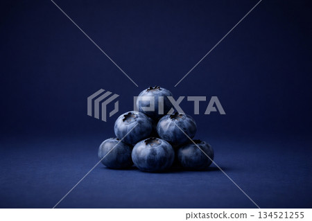 Blueberries stacked in a pyramid on a deep navy background 134521255
