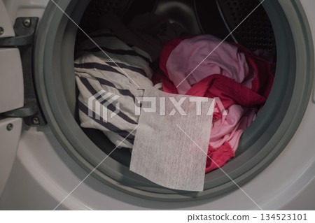 open washing machine full of colorful clothes with color catcher sheet for laundry protection open washing machine full of colorful clothes with color catcher sheet for laundry protection 134523101