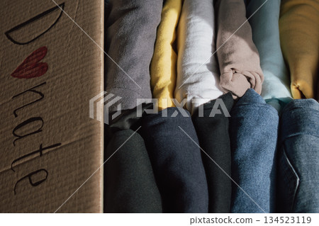 Box of neatly folded clothes ready for donation at home, highlighting generosity and community spirit on a sunny day Box of neatly folded clothes ready for donation at home, highlighting generosity and community spirit on a sunny day 134523119