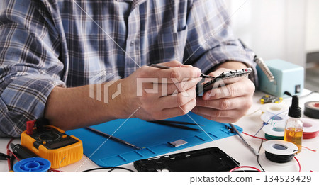 Service Technician Fixing Broken Smartphone In Service Center Service Technician Fixing Broken Smartphone In Service Center 134523429