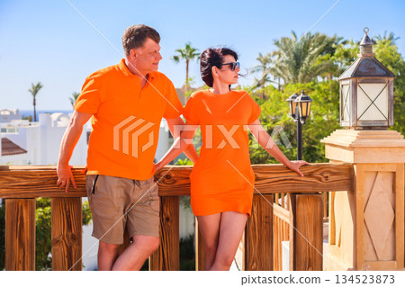 Adult lovers in bright orange clothes on holiday together at a resort Adult lovers in bright orange clothes on holiday together at a resort 134523873