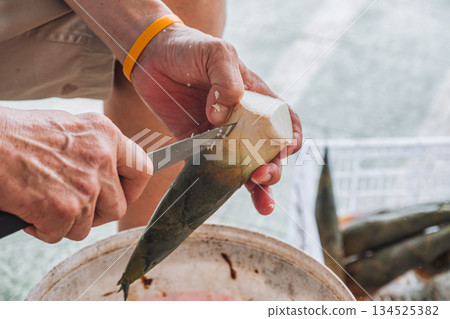 Farmer peeling bamboo shoot with knife in local market Farmer peeling bamboo shoot with knife in local market 134525382
