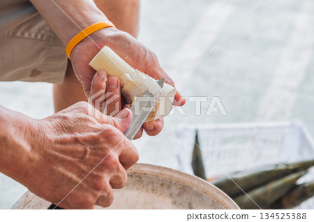 Farmer peeling bamboo shoot with knife in local market Farmer peeling bamboo shoot with knife in local market 134525388