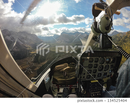 Helicopter cockpit flying over scenic mountain valley in autumn 134525404