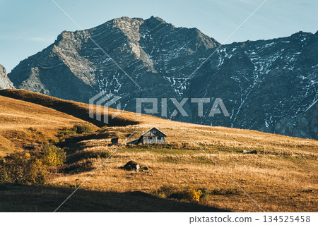 Rustic hut on dry hill with rocky mountain in autumn at French Alps Rustic hut on dry hill with rocky mountain in autumn at French Alps 134525458