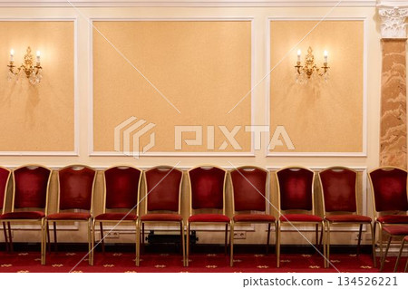 Stylish Arrangement Of Crimson Seats Complemented By Ornate Lighting And Decorative Wall Features Stylish Arrangement Of Crimson Seats Complemented By Ornate Lighting And Decorative Wall Features 134526221