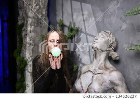 Woman gestures with bright green sphere near ancient stone statue 134526227