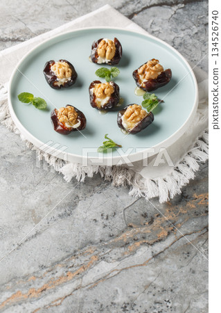 ramadan food, date fruit served with cheese and walnuts in a porcelain plate closeup. Vertical 134526740
