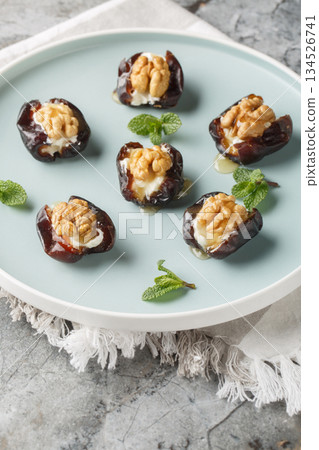 Close-up of dates stuffed with cream cheese, walnuts and honey in a plate. Vertical 134526741