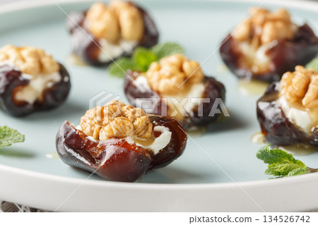 Arabic stuffed dates with cream cheese, walnuts and honey close-up in a plate. Horizontal Arabic stuffed dates with cream cheese, walnuts and honey close-up in a plate. Horizontal 134526742