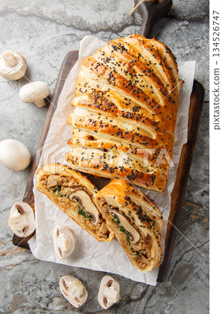 Appetizing mushroom pie or wellington vegetarian closeup on the wooden board. Vertical top view Appetizing mushroom pie or wellington vegetarian closeup on the wooden board. Vertical top view 134526747