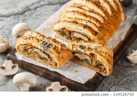 Vegetarian Wellington Tender mushrooms wrapped up in a flaky vegan puff pastry closeup on the wooden board. Horizontal Vegetarian Wellington Tender mushrooms wrapped up in a flaky vegan puff pastry closeup on the wooden board. Horizontal 134526750