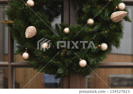 A christmas wreath with branches and golden balls on a door A christmas wreath with branches and golden balls on a door 134527623