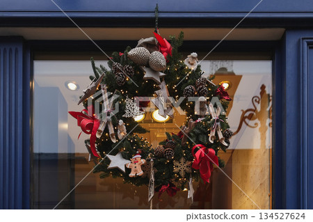 Christmas wreath with red bows golden balls on the branches and on a glass door 134527624