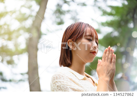 A woman praying in the sunlight filtering through the trees A woman praying in the sunlight filtering through the trees 134527862