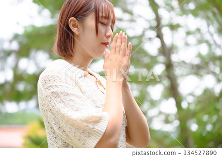一位女子在綠意盎然的環境中靜靜祈禱。 134527890