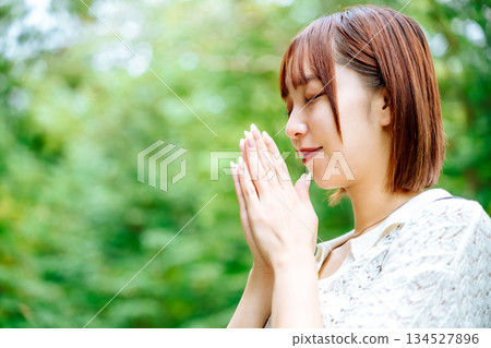 一位在自然中祈禱的女性的側影 134527896