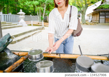A woman purifying her hands with a ladle at a shrine 134527906