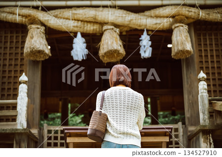 Back view of a woman praying at a shrine 134527910
