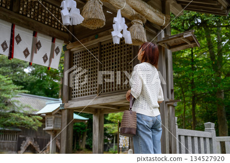 Back view of a woman looking up at the shimenawa rope at a shrine 134527920