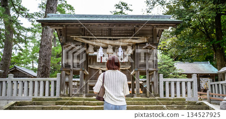 一名女子抬頭望神社的禮拜殿。 一名女子抬頭望神社的禮拜殿。 134527925